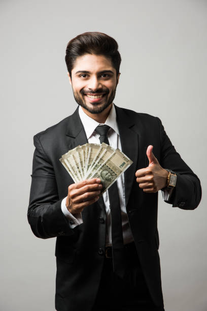 счастливый бородатый индийский бизнесмен, держащий вентилятор в руке, индийские купюры рупии валюты 500 , стоя изолированные на белом фоне - greed currency men happiness стоковые фото и изображения