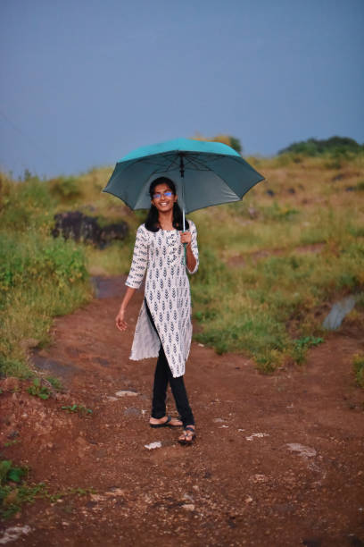 istock Young woman standing with umbrella 1182069509