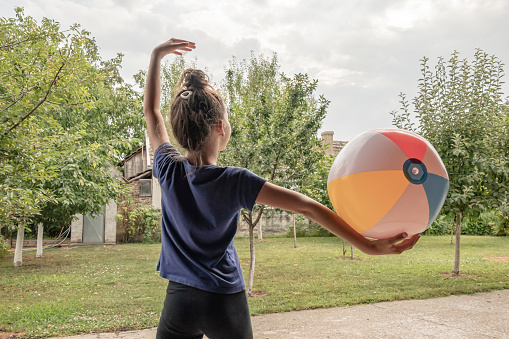Cute Female Child with Twisted Hair is Enjoying in Playing with Large Beach Ball in the Backyard of Country House.