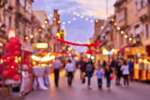 Defocused crowd of people during Christmas fair an old town street with colorful Christmas lights. Traditional Christmas market and shopping time concept