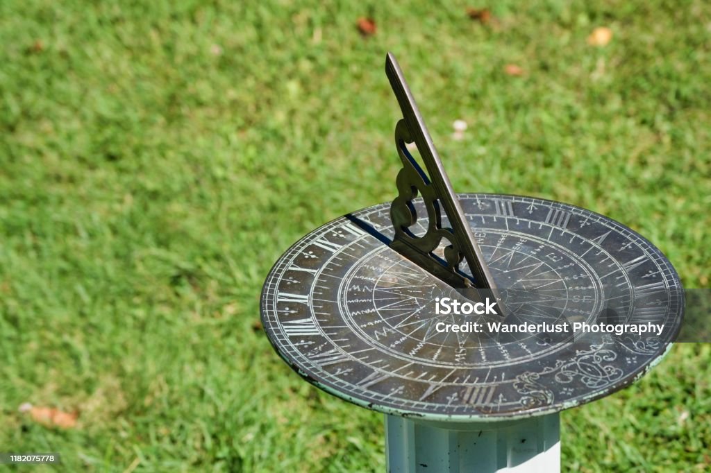 Vintage metal sundial in a park Vintage metal sundial in the sunlight, on a post in the grass Sundial Stock Photo