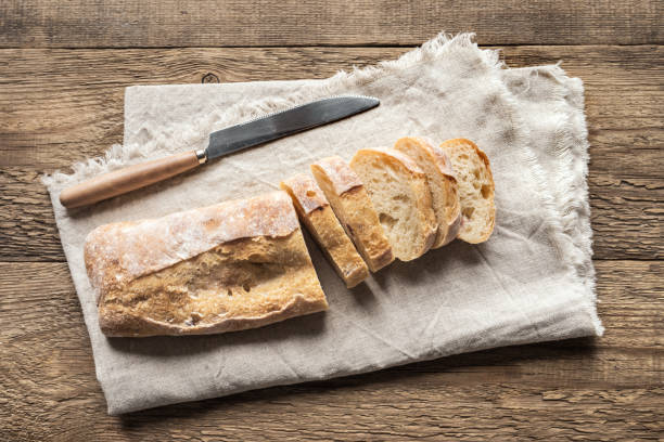 Ciabatta Bread Ciabatta - Fresh Homemade Italian Bread sliced on napkin, wooden table, top view. ciabatta stock pictures, royalty-free photos & images