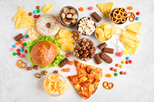 Assortment of Unhealthy Food on white, top view, copy space. Unhealthy eating, junk food concept.