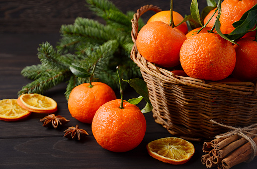 Fresh tangerine clementines with spices on dark wooden background, Christmas concept, selective focus.