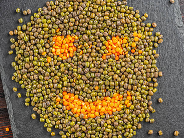 un muso sorridente fatto di fagioli di poltiglia di soia e lenticchie si trova sulla superficie dell'ardesia - mash bean foto e immagini stock