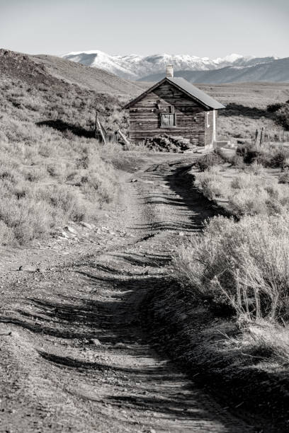 istock Winding road leads wo a rustic old cabin with snow covered mountains 1182087745