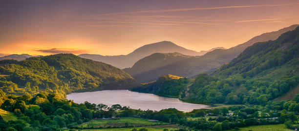 The Sun shining through a mountain pass over Llyn Gwynant in Snowdonia The Sun shining through a mountain pass over Llyn Gwynant, Snowdonia (Eryri), Wales (Cymru), UK llyn gwynant stock pictures, royalty-free photos & images