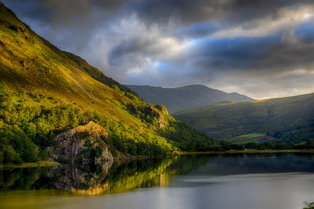 first sun on shinning gallt y wenallt next to llyn gwynant after a strom in snowdonia - nant gwynant imagens e fotografias de stock