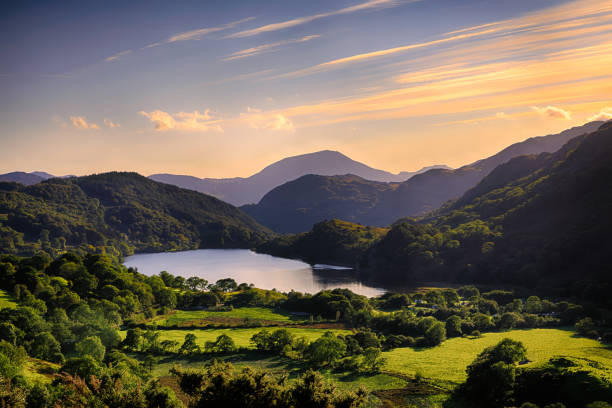 The Sun shining across a mountain and into Llyn Gwynant in Snowdonia The Sun shining across a mountain and into Llyn Gwynant, Snowdonia (Eryri), Wales (Cymru), UK llyn gwynant stock pictures, royalty-free photos & images
