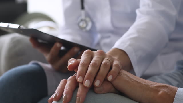 Female doctor holding hand of senior grandmother patient, closeup view