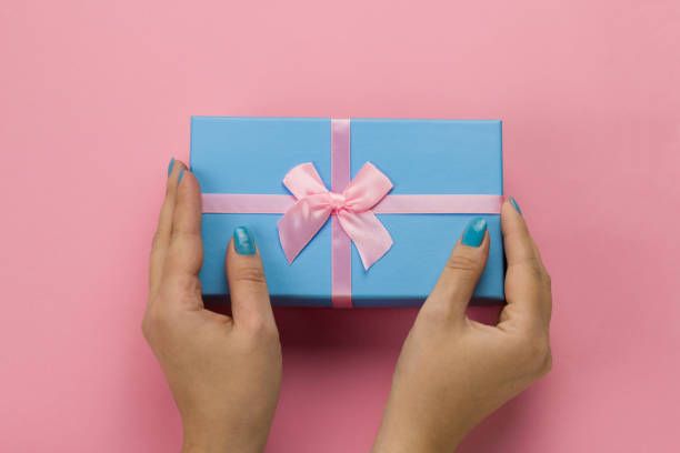 istock female hands holding blue gift box with festive pink bow on a soft pink background 1182094050