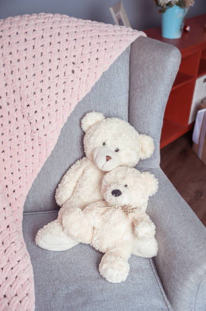 istock Two white toy teddy bears on a chair and a soft pink plaid 1182096604
