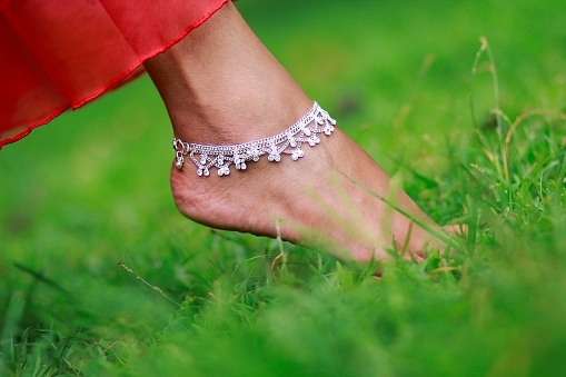 payel a foot jewelery worn in the green grassy background.