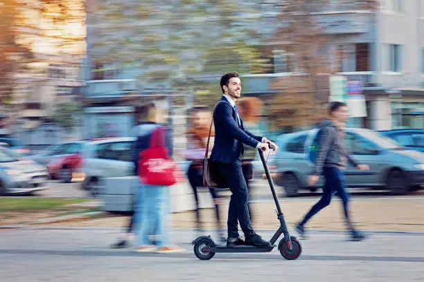 Businessman is riding electric scooter in the city
