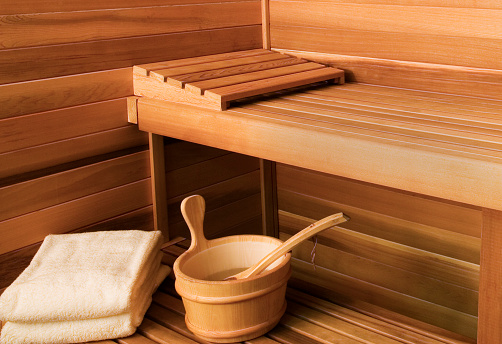 Close-up shot of inside of sauna showing bench, towels and pail.