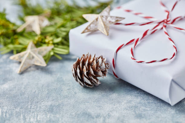 istock Pine cone and Christmas present on bright wooden background. Close up. 1182110441
