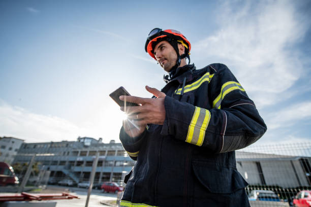 Firefighters in a rescue operation training, Man using a Smart Phone Firefighters in a rescue operation training; all logos removed. Slovenia, Europe. Nikon. rescue services occupation stock pictures, royalty-free photos & images