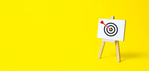 Photo of Sign stand with an arrow in the target on a yellow background. Hit exactly on center. Tactics of advertising targeting. advertise campaigns. Goal Achievement and Purposefulness