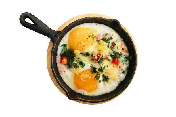 istock Fried eggs with vegetables in frying pan isolated on white background. Top view. 1182121973