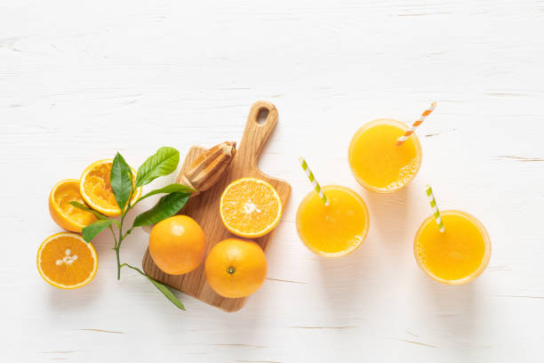 jugo de naranja. jugo recién exprimido en vasos y frutas frescas con hojas, vista desde arriba - zumo de naranja fotografías e imágenes de stock
