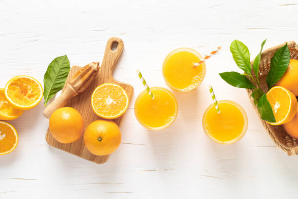 апельсиновый сок. свежевыжатый сок в стаканах и свежие фрукты с листьями, вид сверху - smoothie fruit orange juice стоковые фото и изображения