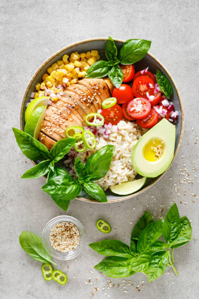istock Buddha bowl with grilled chicken breast, tomato, onion, corn, avocado, fresh basil salad and rice, healthy balanced eating for lunch 1182128552