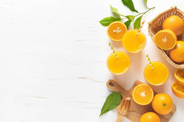 апельсиновый сок. свежевыжатый сок в стаканах и свежие фрукты с листьями, вид сверху - freshly squeezed стоковые фото и изображения