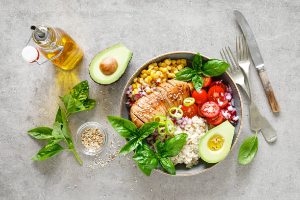istock Buddha bowl with grilled chicken breast, tomato, onion, corn, avocado, fresh basil salad and rice, healthy balanced eating for lunch 1182128648