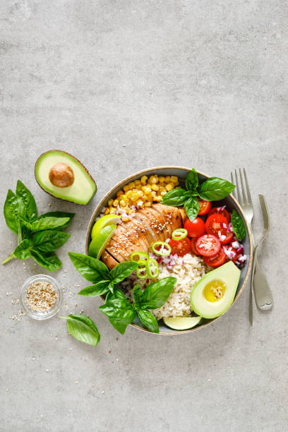 istock Buddha bowl with grilled chicken breast, tomato, onion, corn, avocado, fresh basil salad and rice, healthy balanced eating for lunch 1182128681