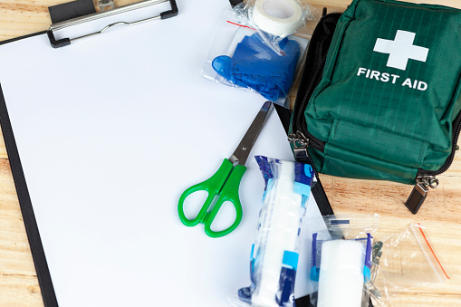 Kit de primeros auxilios verde en una mesa con un portapapeles photo