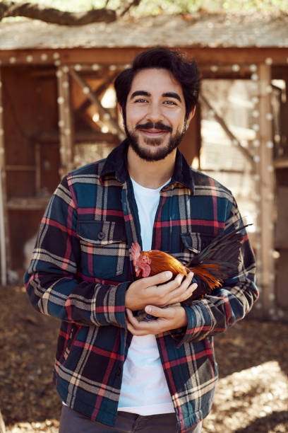 istock Smiling young farmer standing with a rooster outdoors 1182131354