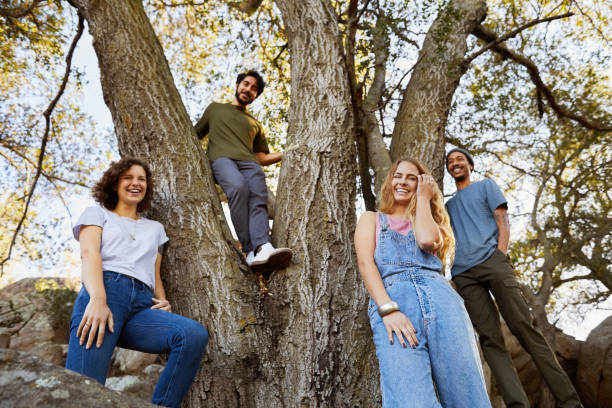 istock Laughing friends standing together around a tree in the forest 1182141991