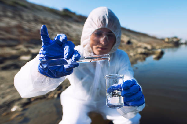 experte d'écologiste féminin dans des vêtements protecteurs examinant la qualité et la pureté de l'eau. sauvez l'environnement. - toxic substance dirt pollution scientific experiment photos et images de collection