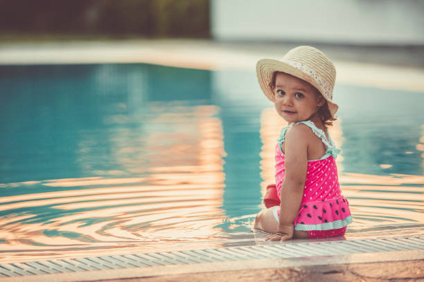 bambina seduta a bordo piscina - 12 23 mesi foto e immagini stock