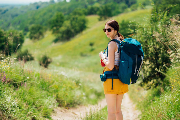 Young female hiker with a thermos and a backpack enjoying on the mountain.