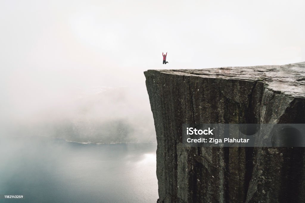 Hiker on Pulpit rock - Preikestolen Pulpit rock - Preikestolen - Norway. Walking routes, exploration and activities of tourists, mountaineers and travelers. Tourist attraction. Crowds of tourist go on a hike to reach the rock. Kristiansand Stock Photo