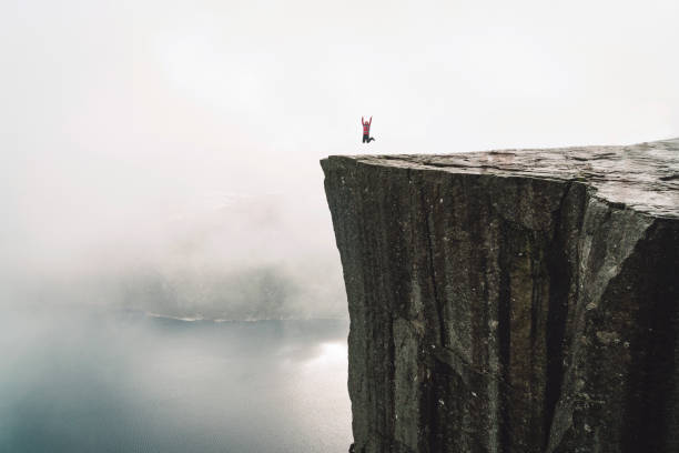 Hiker on Pulpit rock - Preikestolen Pulpit rock - Preikestolen - Norway. Walking routes, exploration and activities of tourists, mountaineers and travelers. Tourist attraction. Crowds of tourist go on a hike to reach the rock. more og romsdal county stock pictures, royalty-free photos & images
