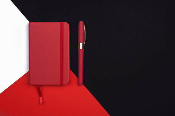 istock red Notepad with pen on red, white and black background. Top view. 1182143318
