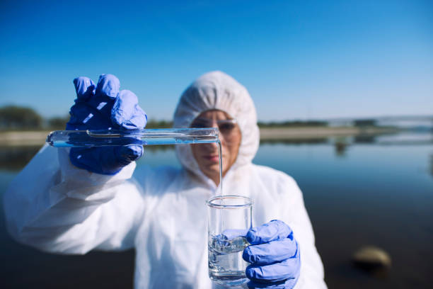 fermez-vous vers le haut de la vue de l'écologiste échantillonnant l'eau de la rivière avec le tube d'essai. examen du niveau de pollution. conserver l'eau et l'environnement. - toxic substance dirt pollution scientific experiment photos et images de collection