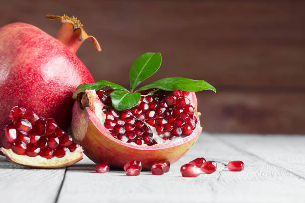 istock Fresh ripe juicy whole and split pomegranate fruit with leaves on white rustic background 1182143682
