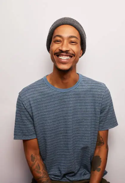 Photo of Smiling young man with tattoos standing against a gray background