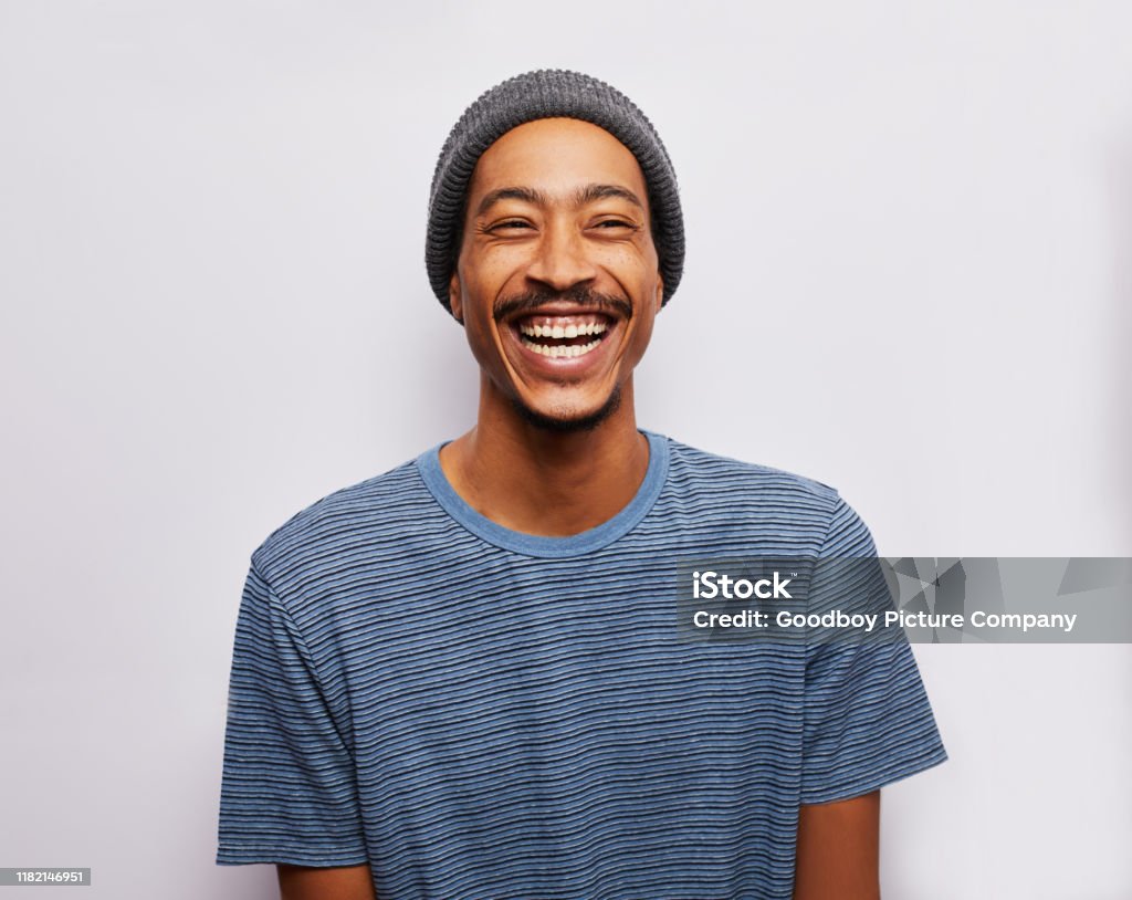 Lachender junger Mann steht vor grauem Hintergrund - Lizenzfrei Männer Stock-Foto