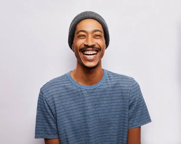Photo of Laughing young man standing against a gray background