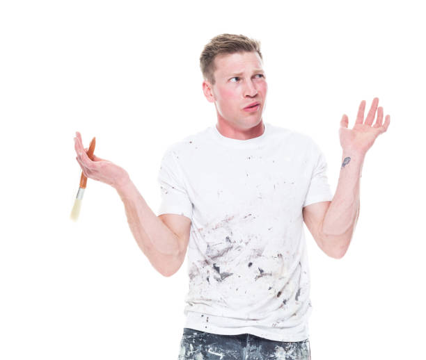 one person / front view / waist up of 20-29 years old adult handsome people caucasian young men / male painter / house painter standing in front of white background wearing t-shirt / shirt / jeans who is confusion / uncertainty who is painting - beautiful men young adult 25 30 years imagens e fotografias de stock