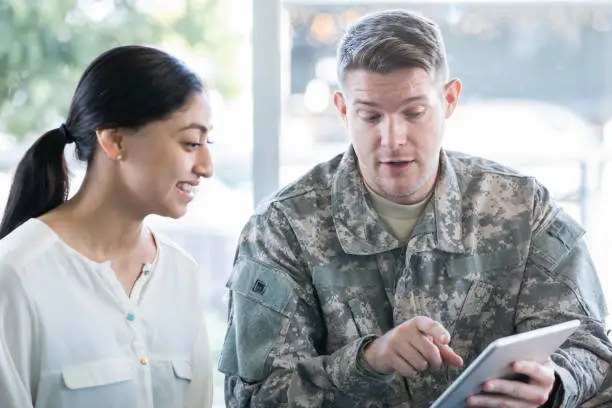 Photo of Military man holding digital tablet in recruitment office