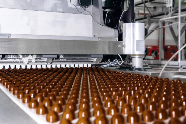 chocolate toppings on the conveyor of a confectionery factory close-up rows of toppings for chocolates manufactured by machine, on a conveyor of a chocolate factory chocolate truffle making stock pictures, royalty-free photos & images