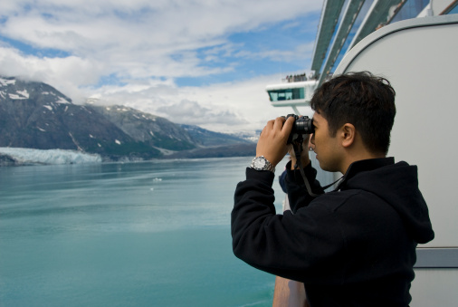 Young Man on Cruise Ship Looks Through Binoculars in Alaska