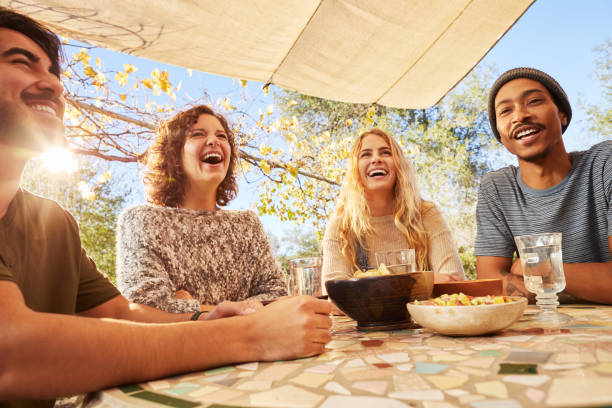 istock Laughing group of friends sitting outdoors having lunch together 1182160190
