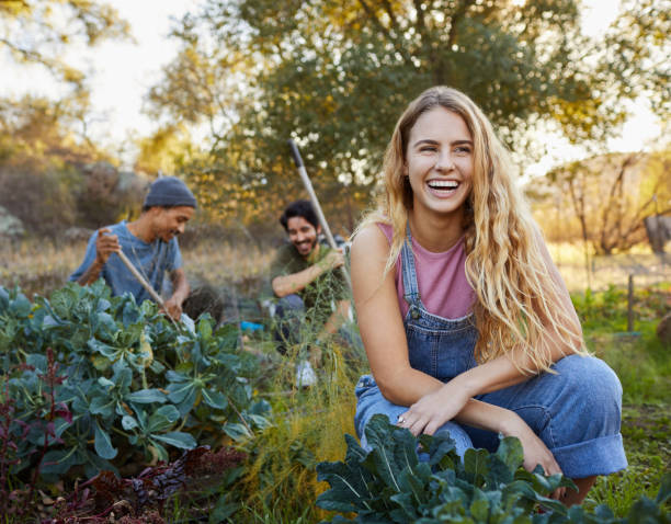 istock Young woman laughing while working with friends on a farm 1182160892