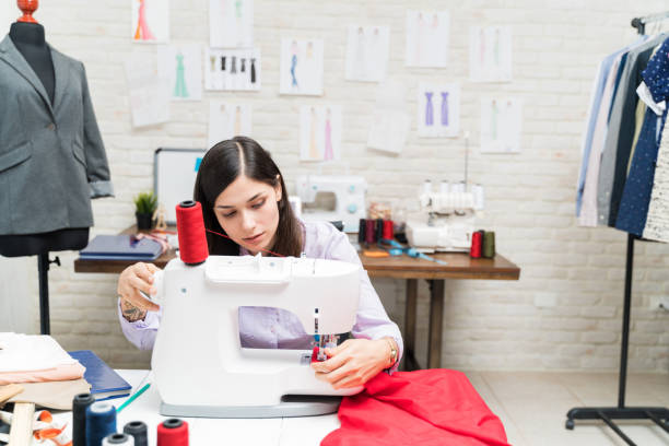 istock Dressmaker stitching fabric on sewing machine at desk in studio 1182165186